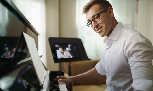 Online Klavierunterricht für Erwachsene Mann schaut auf die Tastatur eines Klaviers