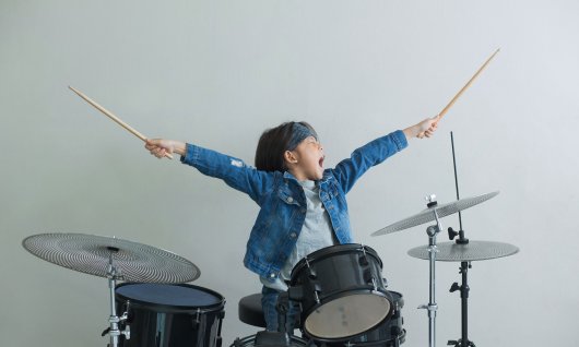 Online Percussion lernen für Kinder Kind streckt Drumsticks in die Luft