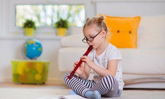 Mädchen mit Brille spielt Flöte