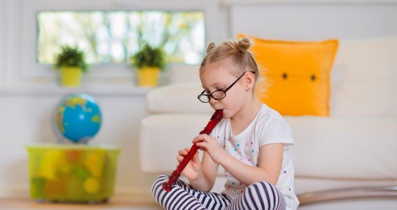 Mädchen mit Brille spielt Flöte