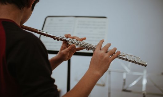Online Querflöte spielen für Jugendliche Junge spielt Querflöte und schaut auf den Notenständer
