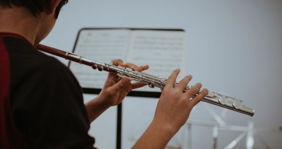 Junge spielt Querflöte und schaut auf den Notenständer