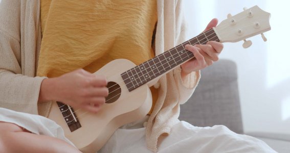 Person spielt sitzend Ukulele