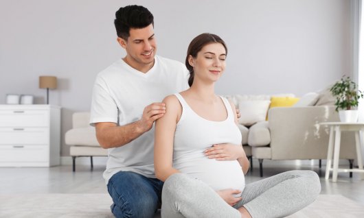 Werdender Papa massiert seiner schwangeren Frau den Nacken