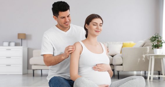 Werdender Papa massiert seiner schwangeren Frau den Nacken