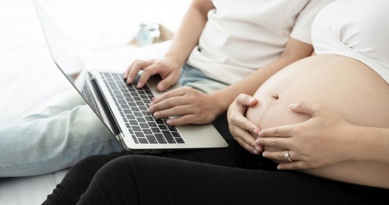 Werdender Papa und schwangere Frau schauen am Laptop Geburtsvorbereitungskurs