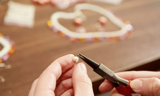 Hände einer Frau biegen einen selbstgemachten Ohrring zurecht