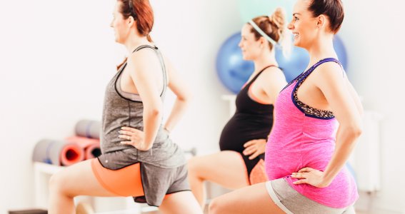 Drei schwangere Frauen machen Pilatesübungen