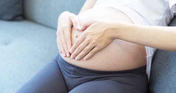 Schwangere Frau sitzt auf Couch