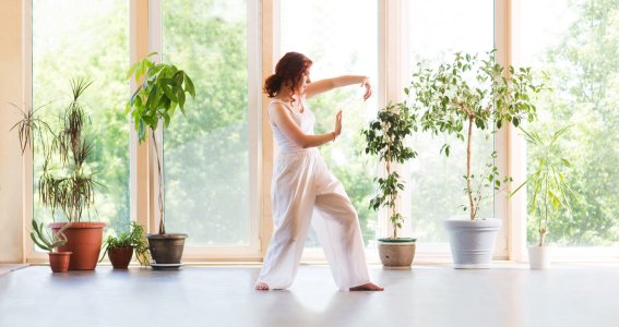 Frau macht Qigong im Wohnzimmer