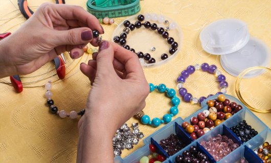 Frau, die Armbänder mit großen, bunten Perlen herstellt