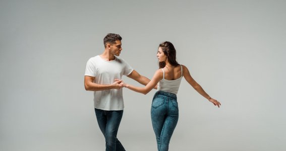 Ein junges Paar in blauen Jeans und weißen Tops in Tanzpose
