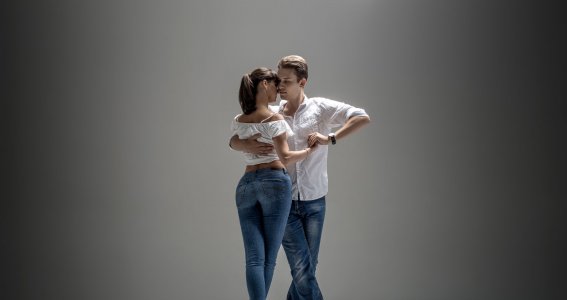Zwei junge Menschen in blauen Jeans und weißen Tops tanzen