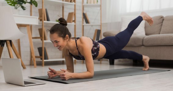 Frau macht Pilates vor einem Laptop