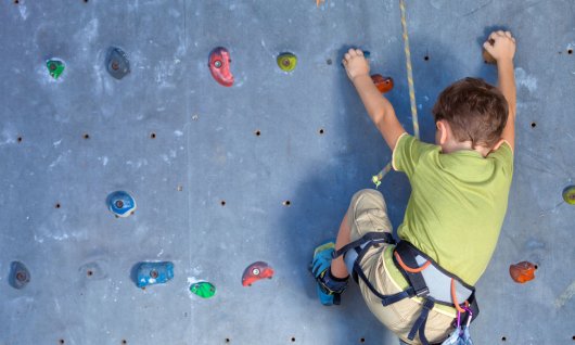 Kind klettere an einer Kletterwand