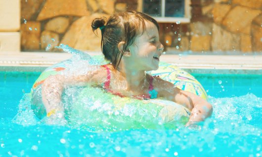 Kleines Mädchen ist in einem Pool in einem Schwimmring.
