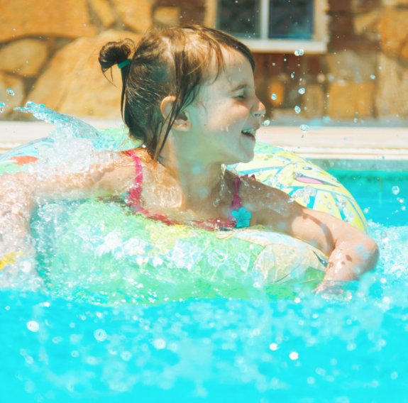 Kleines Mädchen ist in einem Pool in einem Schwimmring.