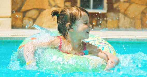 Kleines Mädchen ist in einem Pool in einem Schwimmring.