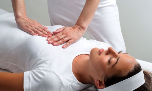 Frau liegt auf dem Rücken und erhält eine Massage