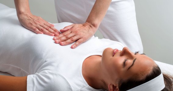 Frau liegt auf dem Rücken und erhält eine Massage