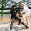 Ein Mann hilft einer Frau, die auf dem Skateboard steht und einen Trick versucht