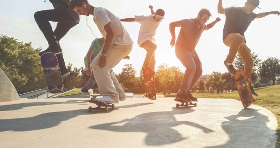 Eine Gruppe junger Männer versuchen einen Sprung mit dem Skateboard