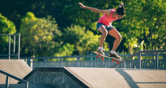 Eine junge Frau im Skatepark versucht einen Skateboard-Trick