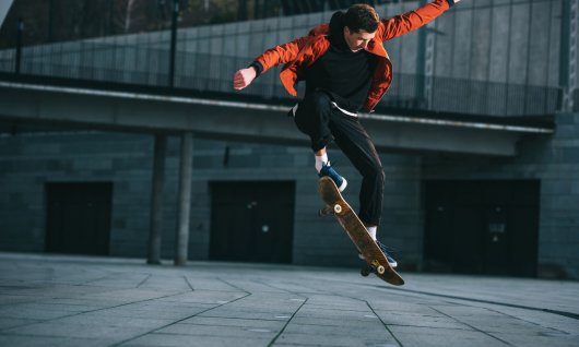 Einer Mann springt mit dem Skateboard einen Ollie