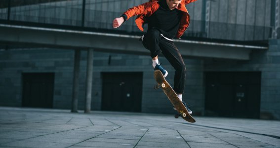 Einer Mann springt mit dem Skateboard einen Ollie