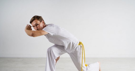 Ein junger Mann trainiert in einem leeren Raum Capoeira-Positionen