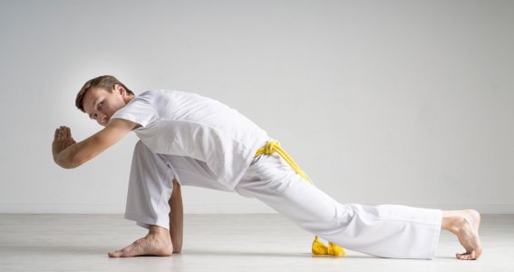 Ein junger Mann trainiert in weißer Kleidung Capoeira