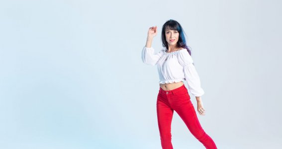 Eine Frau in roten Jeans tanzt vor einem weißen Hintergrund