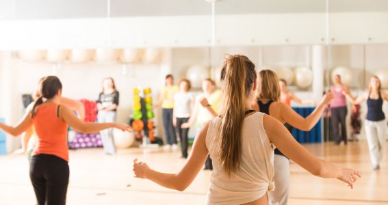 Eine Gruppen von Frauen tanzt vor einem Spiegel im Tanzstudio