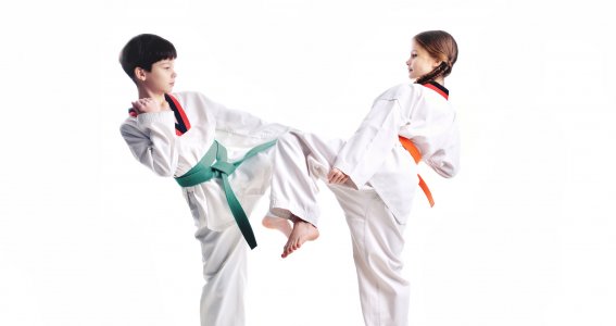 Ein Junge und ein Mädchen in Taekwondo-Anzügen stehen in Kampfpose ohne Hintergrund