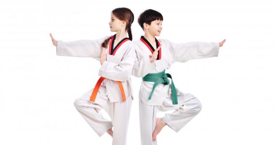 Ein Junge und ein Mädchen stehen mit Rücken zueinander in weißen Taekwondo-Anzügen und posieren