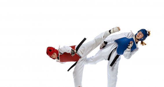 Zwei Jugendliche in Taekwondo Anzügen und Schutzausrüstung trainieren Kampfkunst