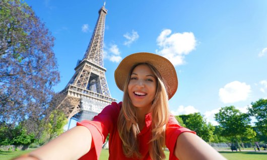 Frau macht ein Selfie vor dem Eiffelturm