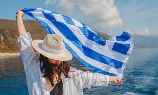 Griechische Flagge wird von einer Frau hochgehalten
