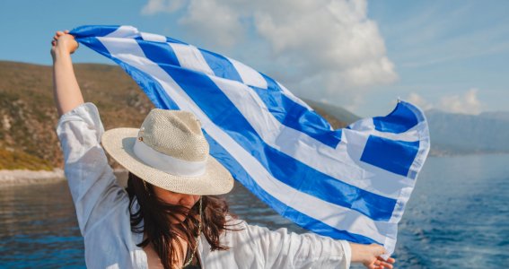 Griechische Flagge wird von einer Frau hochgehalten