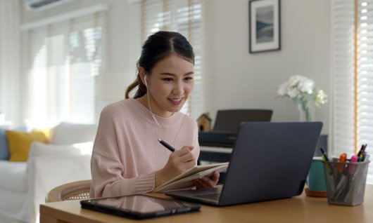 Frau sitzt mit Kopfhörern am Laptop