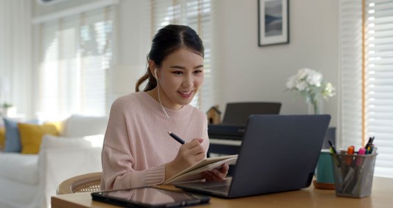 Frau sitzt mit Kopfhörern am Laptop