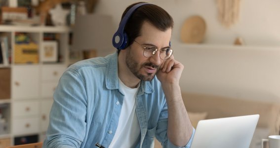 Mann arbeitet am Laoptop und hält einen Stift in der Hand