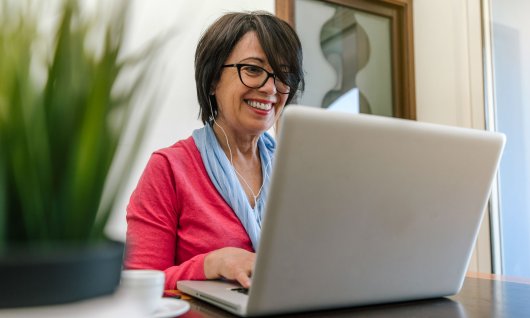 Frau lächelt und tippt auf die Tastatur ihres Laptops