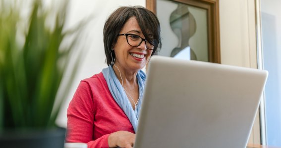 Frau lächelt und tippt auf die Tastatur ihres Laptops
