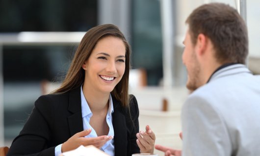 Frau und Mann unterhalten sich an einem Tisch