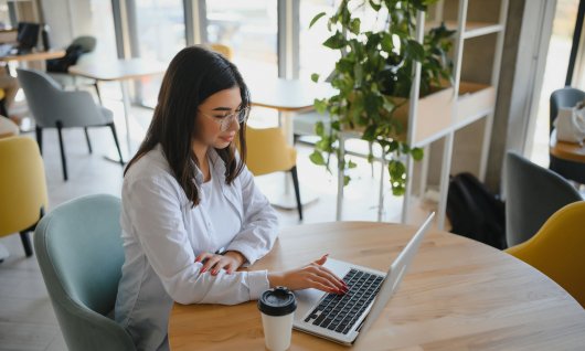 Frau sitzt auf einem Stuhl und arbeitet am Laptop