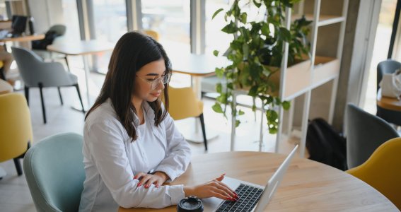 Frau sitzt auf einem Stuhl und arbeitet am Laptop