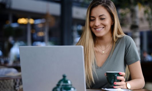 Frau trinkt Kaffee und schaut auf ihrem Laptop