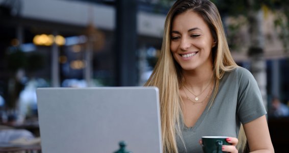 Frau trinkt Kaffee und schaut auf ihrem Laptop