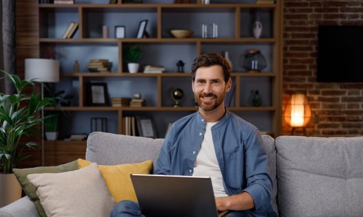 Mann sitzt auf der Couch mit einem Laptop